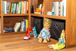lalka siedząca na podłodze obok półki na książki w obiekcie Apartmán Kafe s postelí, střed Mikulova w mieście Mikulov