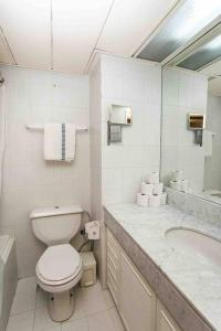 a white bathroom with a toilet and a sink at Orchid Hotel Beachfront 2BR Apartment in Tel Aviv