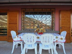 una mesa con cuatro sillas y un arreglo floral en ella en La Mosa - Villa ai Prati di Cavedago, nel comprensorio del parco Adamello-Brenta, en Cavedago