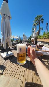 a person holding a glass of beer on a table at a beach at Flat For Rent Near The Beach, Konyaaltı, Antalya in Antalya