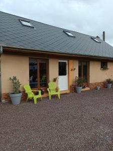 a house with two green chairs in front of it at L'écurie in Méneslies