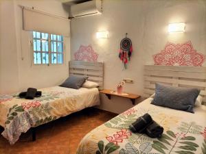 Zimmer mit 2 Betten, einem Tisch und Fenstern in der Unterkunft VILLA LOS ARCOS in Málaga