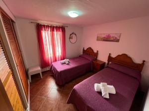 two beds in a room with purple sheets at Casa Montse in Cala Galdana