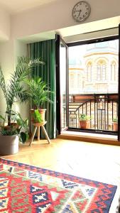 Diana's Flat-Bucharest - Old City في بوخارست: غرفة بباب زجاجي كبير فيها نباتات وساعة