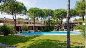 a swimming pool in front of a building with trees at Quadrifoglio 43 in Bibione