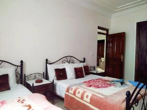1 dormitorio con 2 camas y espejo en Maison Othmane en Esauira