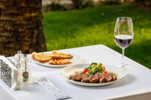une table blanche avec deux assiettes de nourriture et un verre de vin dans l'établissement Luxury Sea View Apartments Rafailovici, à Budva