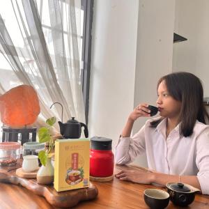 a woman sitting at a table talking on a cell phone at S8 Boutique Hotel near KLIA 1 & KLIA 2 in Sepang