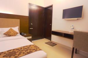 Habitación de hotel con cama y TV en Holy Inn Sylhet, en Sylhet