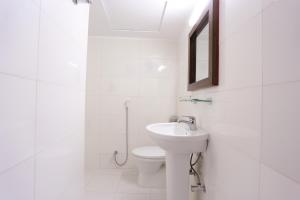 a white bathroom with a toilet and a sink at Holy Inn Sylhet in Sylhet