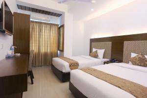a hotel room with two beds and a desk at Holy Inn Sylhet in Sylhet
