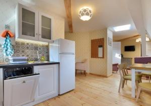 a kitchen with a white refrigerator and a table at Słoneczna Willa & sauny Apartamenty in Kudowa-Zdrój