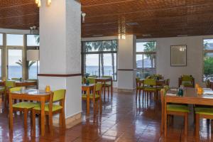 uma sala de jantar com mesas, cadeiras e janelas em Flag Hotel Madeira - Ribeira Brava em Ribeira Brava