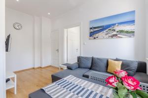 una sala de estar con un sofá azul con un jarrón de rosas en Pod Muralem - Apartamenty Little Heaven, en Ustka