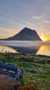 a mountain sitting on the shore of a body of water at Kirkjufell Oceanfront Villa in Grundarfjordur