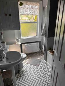 a bathroom with a sink and a toilet and a window at Cosy 19th century two bedroomed home with continental Breakfast in Bath