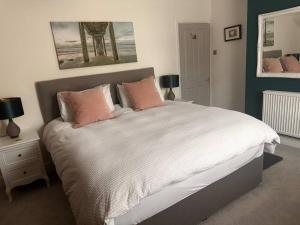 a bedroom with a large white bed with pink pillows at Cosy 19th century two bedroomed home with continental Breakfast in Bath