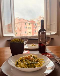 un piatto di pasta su un tavolo con una bottiglia di vino di La Finestra Sul Mare - [Sea View] a Genova