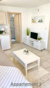 a living room with a white table and a kitchen at Croadriatic Apartments in Vir