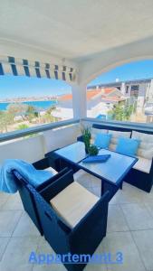 a balcony with blue tables and chairs and a view of the ocean at Croadriatic Apartments in Vir