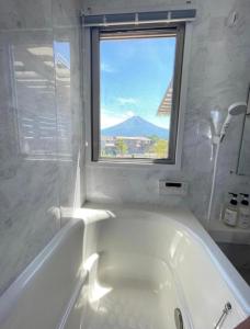 a white bath tub in a bathroom with a window at Necoana Glamping in Fujikawaguchiko