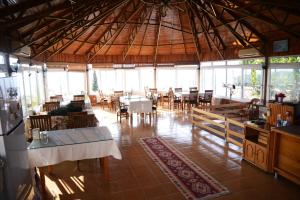 a dining room with tables and chairs and windows at Huzur Hotel in Siğacık