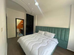 een slaapkamer met een groot wit bed met een groen hoofdeinde bij Lovely Seaview beachfront Apartment in Agadir