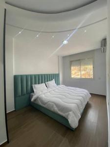 een slaapkamer met een bed met een groen hoofdeinde en een raam bij Lovely Seaview beachfront Apartment in Agadir