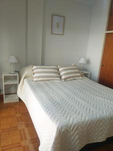 1 cama blanca grande en un dormitorio con 2 lámparas en Miri House en Bahía Blanca