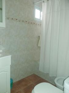 y baño con aseo y cortina de ducha. en Miri House en Bahía Blanca