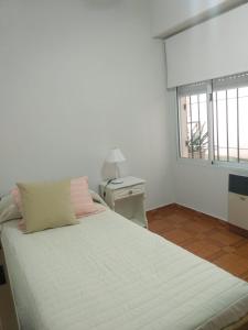 1 dormitorio con 1 cama blanca grande y ventana en Miri House en Bahía Blanca