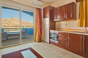 a kitchen with wooden cabinets and a view of the ocean at Royal Beach Hotel in Arkasa