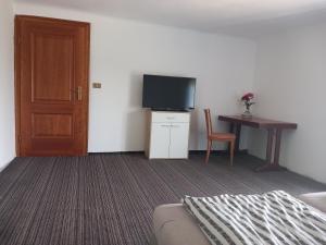 a room with a bed and a television and a table at Casa Marza in Ghioroc