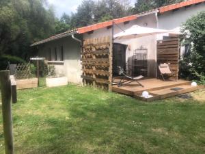 ein Haus mit einer Holzterrasse mit einem Sonnenschirm in der Unterkunft Le paradis des ouches in Aubigny