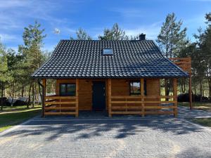 a cabin with a black roof on a brick road at U Progu Lasu in Budy