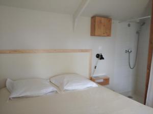 a bedroom with a white bed and a shower at Cabane sous les Chênes in Montagnac