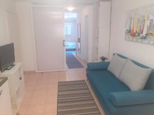 a living room with a blue couch and a television at Apartments Zlata In the Heart of the Old Town, Close to the Beach in Rab