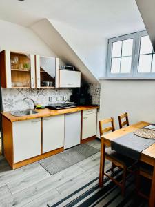 een keuken met witte kasten, een tafel en een wastafel bij Apartmány na Horce in Blata
