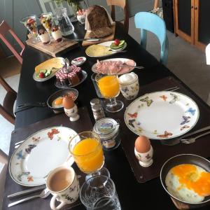una mesa con platos de huevos y vasos de zumo de naranja en B&B Bij tante Teun en Naaldwijk