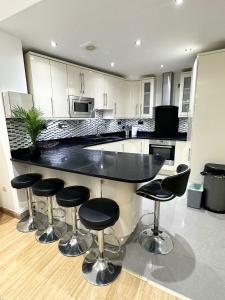 a kitchen with a black counter and bar stools at London Charm - Comfortable Room in Spacious House in London