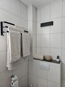 La salle de bains est pourvue de serviettes blanches accrochées au mur. dans l'établissement Gemütliche Wohnung in ruhigem Wohngebiet, à Aschaffenbourg
