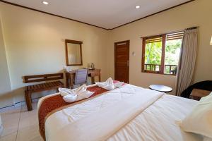 1 dormitorio con 1 cama blanca grande y escritorio en Komodo Lodge, en Labuan Bajo