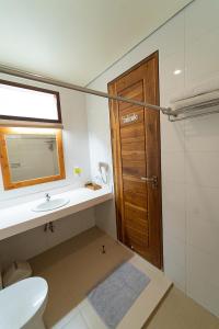 baño con aseo y lavabo y puerta de madera en Komodo Lodge, en Labuan Bajo