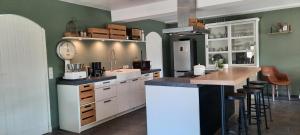 uma cozinha com armários brancos e um balcão com bancos em vakantieboerderij Aardenhof em Sevenum