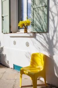 einem gelben Stuhl vor einem Fenster in der Unterkunft Studio les pieds dans l'eau et immense jardin in Carqueiranne