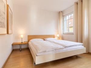 een witte slaapkamer met een bed en een raam bij Grüne Straße FeWo G4 (DG rechts) in Prerow