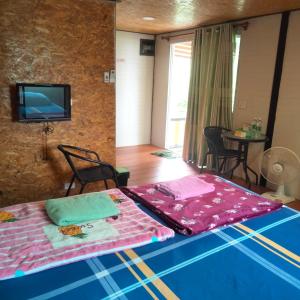 Ban Tha Ngamにあるบ้านสวนริมน้ำวังใหญ่ห้อง a4 วังสามหมอ อุดรธานีの壁にテレビとベッドが備わる客室です。