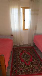 a room with two beds and a window and a rug at Guest house Umar in Tong