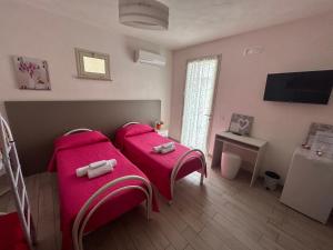 1 dormitorio con 2 camas y mantas rosas en B & B Da Rosa, en Petrosino