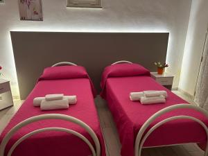 2 camas en una habitación con sábanas rosas y toallas en B & B Da Rosa, en Petrosino